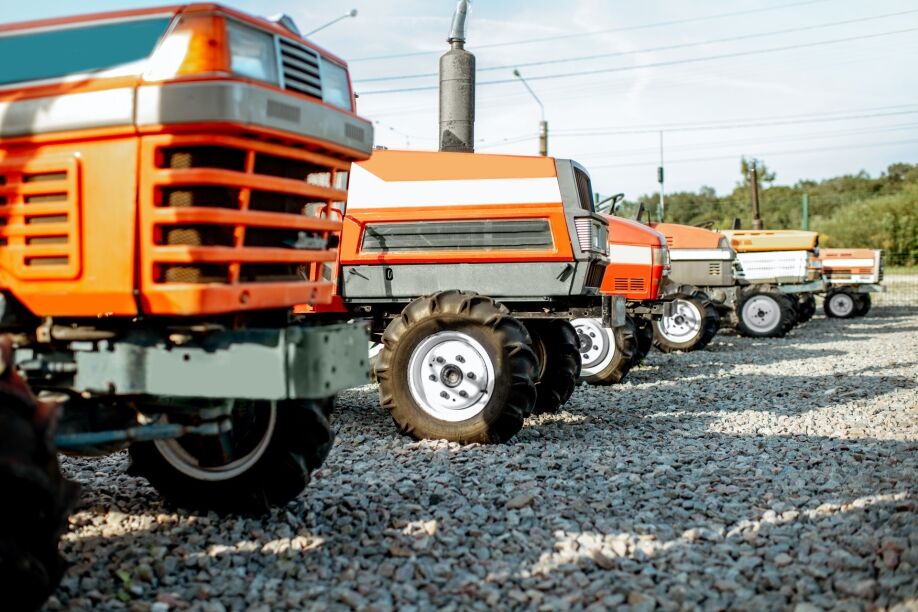 A group of agricultural equipment rentals sit on a gravel lot.