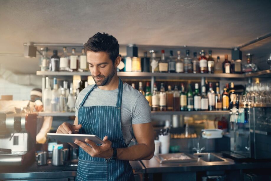 A barista uses smart retail and hospitality software on a tablet.