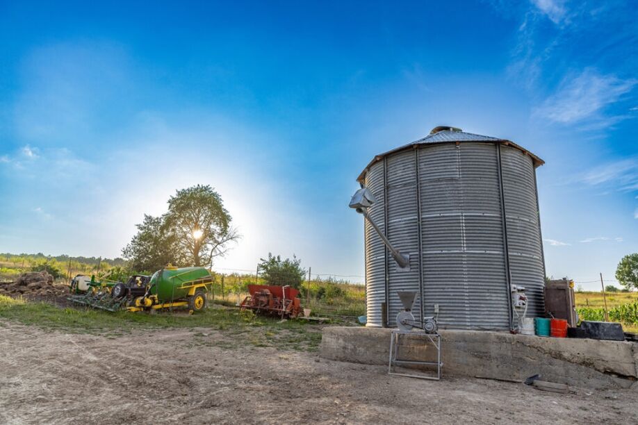 A silo monitored by an IoT silo level monitoring solution sits in a field.