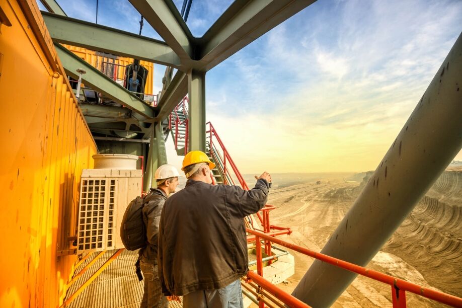 Two coal mine engineers with protective helmets standing on a hu